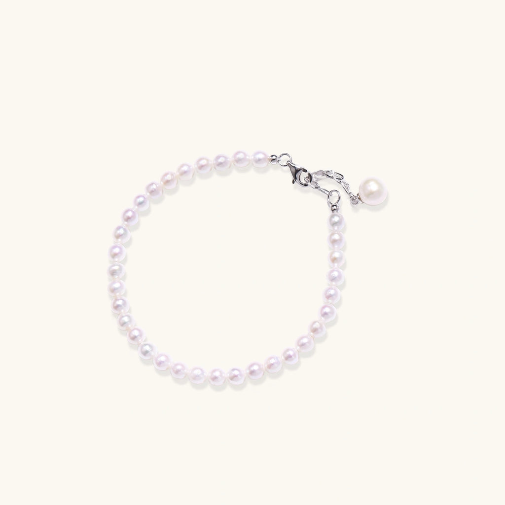Adjustable bracelet featuring lustrous freshwater pearls with rhodium-plated sterling silver clasp on cream background.