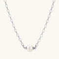 Dainty rhodium-plated silver chain necklace with centered 10mm freshwater pearl and crystal accents on cream background