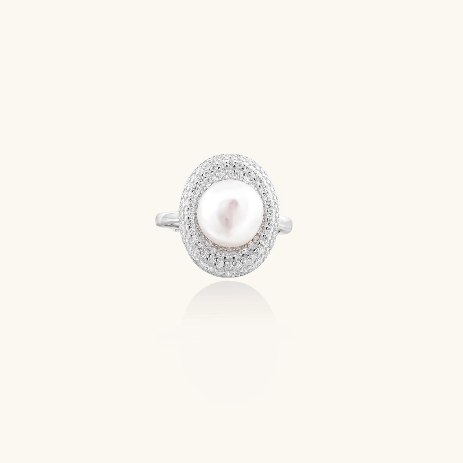 Silver ring with lustrous white pearl center surrounded by sparkling crystal halo on light background.